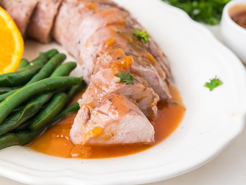 Roasted pork tenderloin glazed with a sweet citrus sauce and served with green beans and fresh orange slices.
