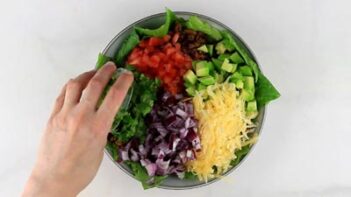 pouring on cilantro in a a salad bowl with other ingredients