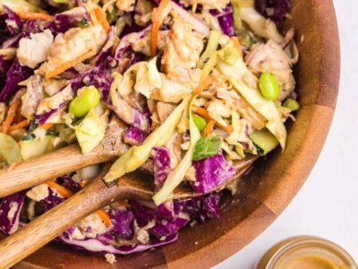 Thai chicken salad with chicken, cabbage, edamame, carrots and cucumber in a wooden bowl.