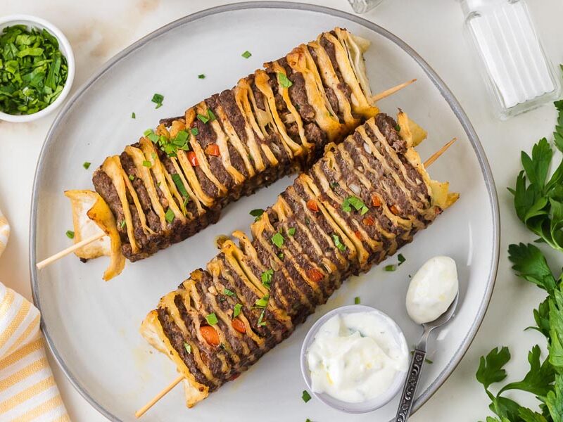 Three tortilla kebabs layered with beef, cheese and tortillas, topped with parsley.
