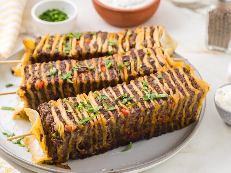 Golden brown tortilla kebabs filled with seasoned beef and vegetables arranged on a serving platter.