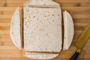 Low carb tortillas trimmed into rectangles and strips on a wooden cutting board.