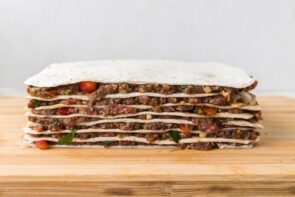 Layered stack of tortillas and seasoned beef filling assembled for tortilla kebabs.