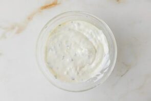 Creamy yogurt dipping sauce mixed in a small glass bowl for serving with tortilla kebabs.