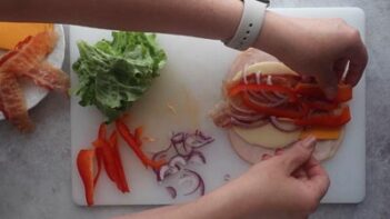 Placing sliced red bell pepper on a wrap.