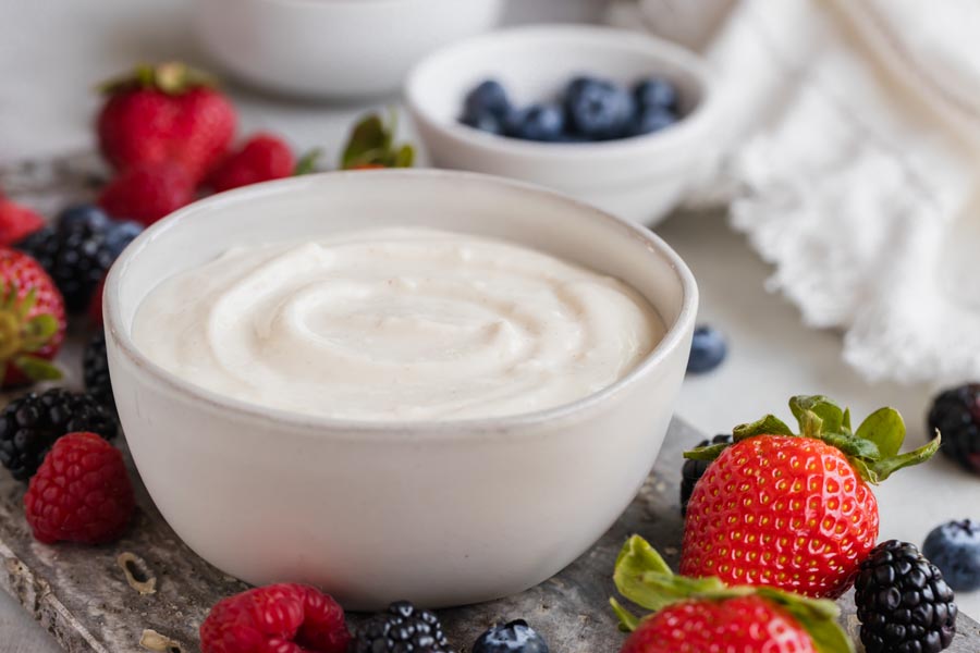 Creamy yogurt dip in a bowl with assorted berries surrounding the bowl.