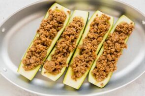 Seasoned ground beef stuffed inside a zucchini boat on a skillet.