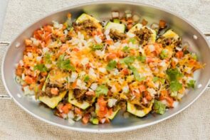 Fresh out of the oven, stuffed zucchini with taco meat and salsa sprinkled all over.